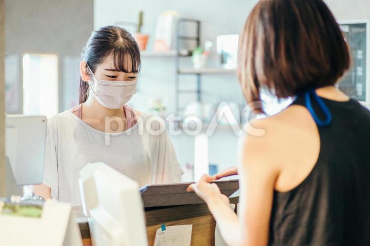 受付でタブレットを見る女性（マスク） スポーツジム,マスク,予約の写真素材