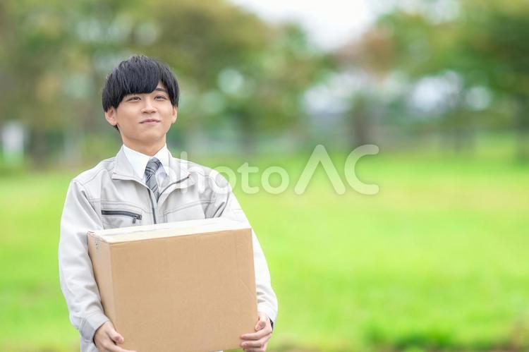 段ボールを持った作業員男性 男性,若い男性,作業服の写真素材