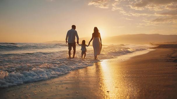 夕焼けの海辺を歩く家族の写真