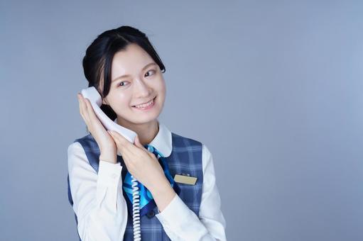 制服姿の女性が電話を耳に当てるの写真