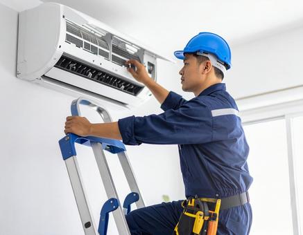 エアコン室内機を修理する男性技術者の写真
