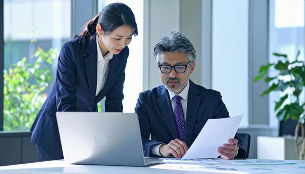 データを見ながら相談する上司と部下 データを見ながら相談する上司と部下の写真