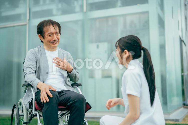 病院の屋上で医療スタッフと話す中高年男性 看護師,介護士,理学療法士の写真素材