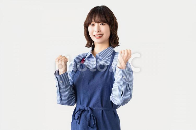 ガッツポーズをするエプロン姿の女性 女性,人物,笑顔の写真素材