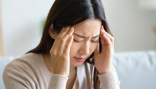 頭を抱えて落ち込む日本人女性 頭を抱えて落ち込む日本人女性の写真