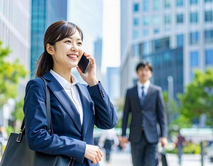 街中で電話をかける若い女性社員 街中で電話をかける若い女性社員の写真