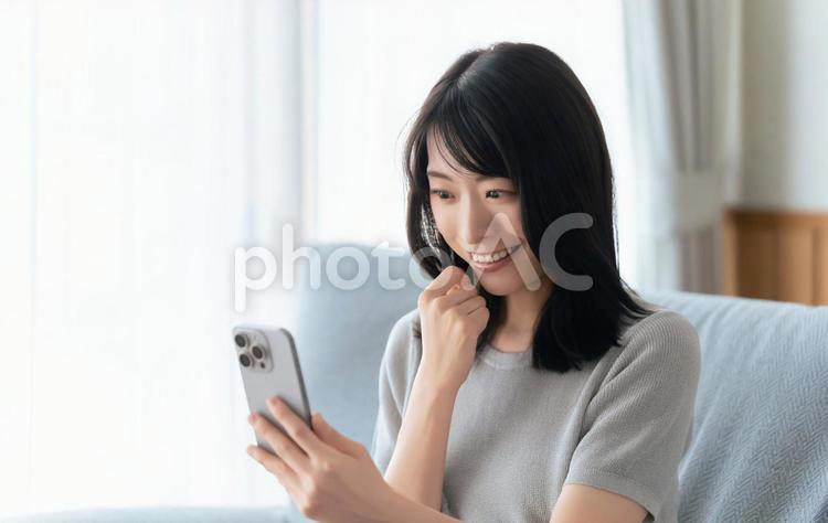 ソファに座ってスマホを使う笑顔の女性 女性,スマホ,スマートフォンの写真素材