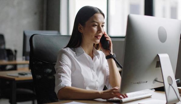 画面を見ながら電話で話すビジネスウーマン 画面を見ながら電話で話すビジネスウーマンの写真
