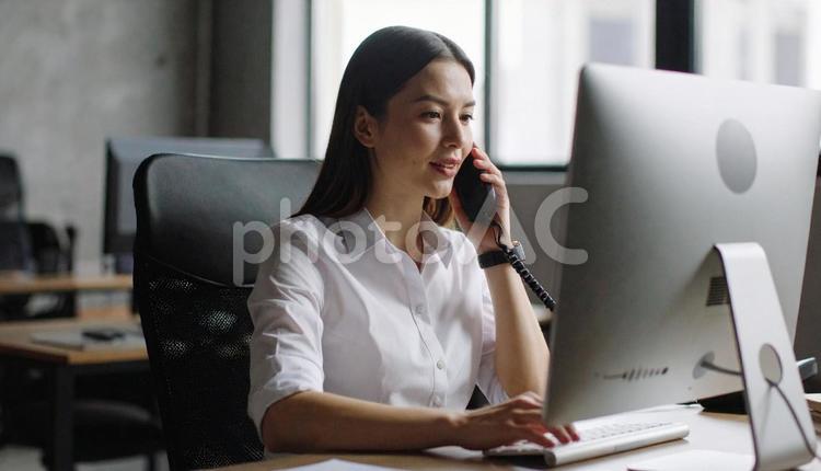 画面を見ながら電話で話すビジネスウーマン 電話,オフィス,ビジネスウーマンの写真素材