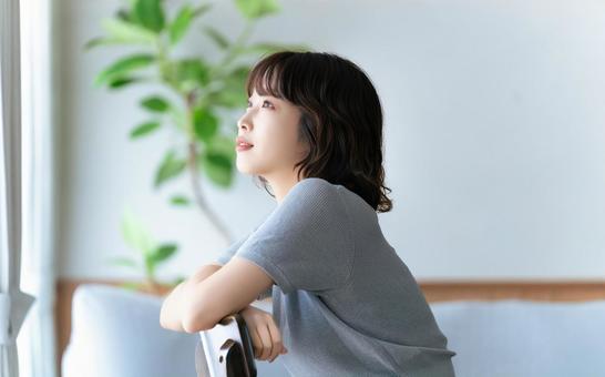 椅子に座って窓の外を見る女性 椅子に座って窓の外を見る女性 女性,椅子,座るの写真素材