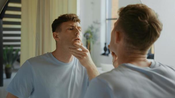 洗面所の鏡で顎を見ている男性 男性,外国人,欧米人の写真素材