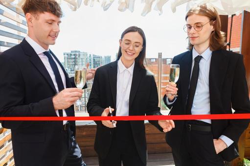 赤いテープをハサミで切る女性 男女,テープカット,赤の写真素材