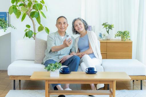 リビングでスマホを見るシニア夫婦 スマホ,シニア,笑顔の写真素材
