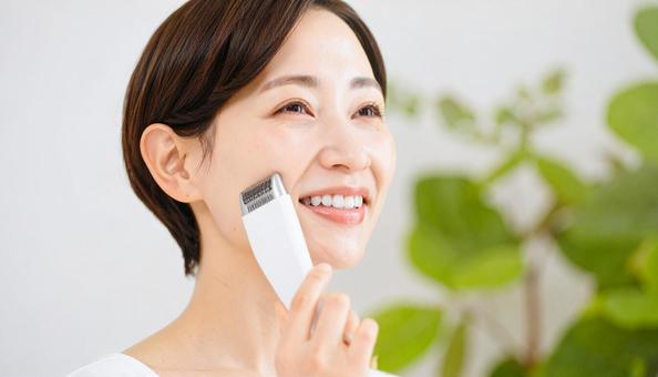 美顔器を頬に当てて美容ケアをする女性の写真