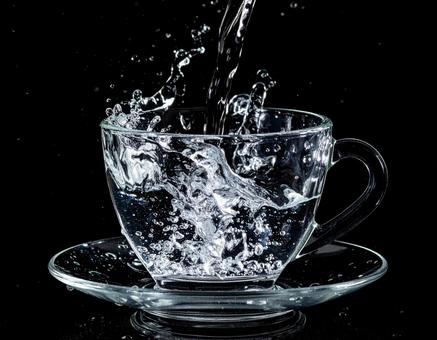 透明のカップから勢いよくあふれる水3 透明のカップから勢いよくあふれる水3の写真
