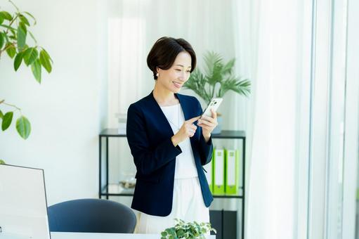 スマホを持つビジネスウーマン スマホを持つビジネスウーマン スマホ,ビジネスウーマン,キャリアウーマンの写真素材