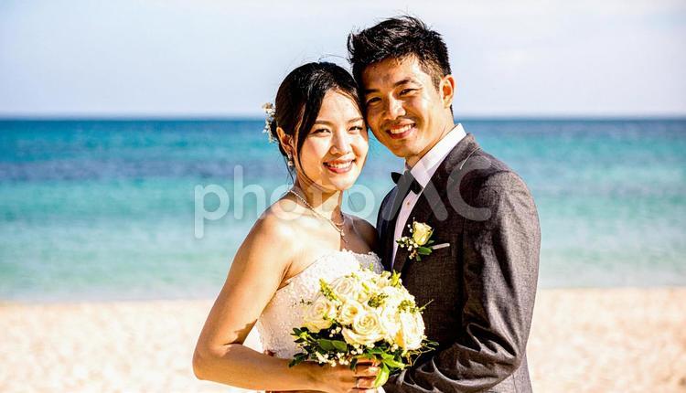 ブーケを持ち顔を見合わせる新郎新婦 海,ウエディング,結婚の写真素材