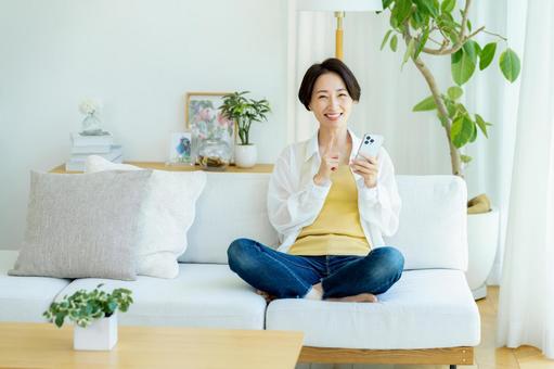部屋でスマホを使うミドル女性 部屋でスマホを使うミドル女性 スマホ,笑顔,女性の写真素材