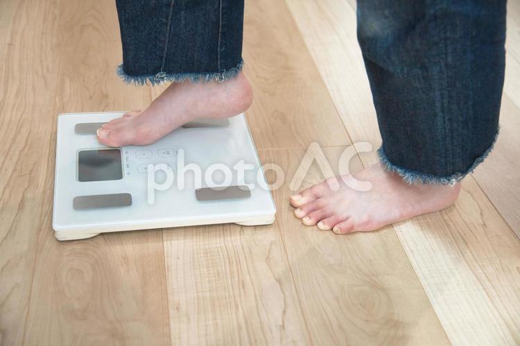 リビングで体重計にそっと足を乗せる女性 体重計,体重管理,健康維持の写真素材