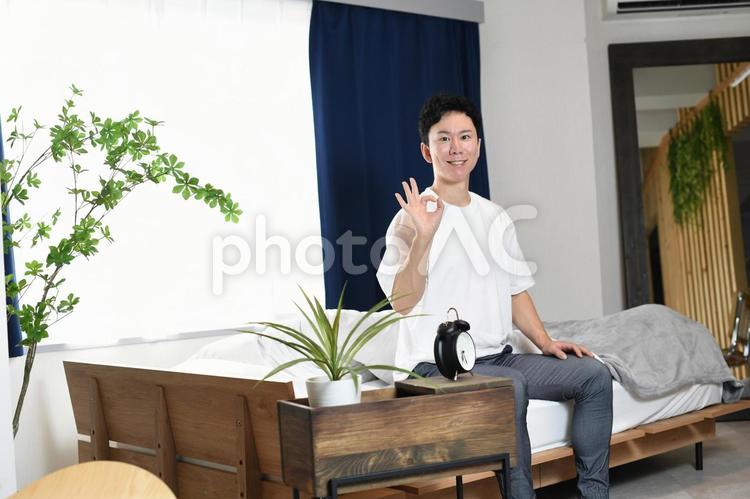 ベッドの上でOKをする若いアジア人男性 ベッド,男性,安眠の写真素材