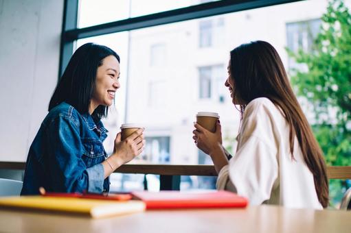 大学のカフェスペースで談笑する女子大生 大学のカフェスペースで談笑する女子大生の写真