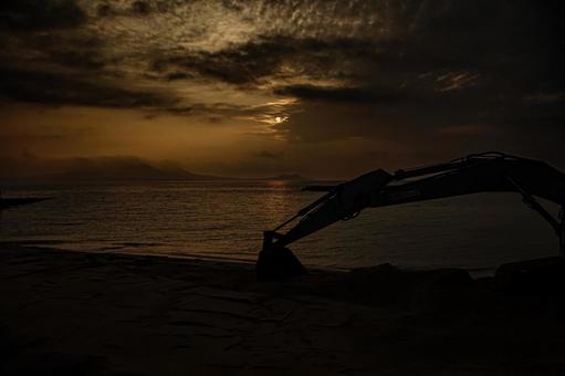 <素材>夜明けの砂浜整地用のショベルカー <素材>夜明けの砂浜整地用のショベルカーの写真
