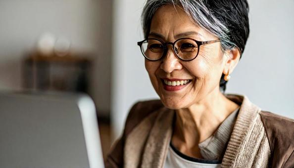 パソコンに向かって笑顔の50代の女性 パソコンに向かって笑顔の50代の女性の写真