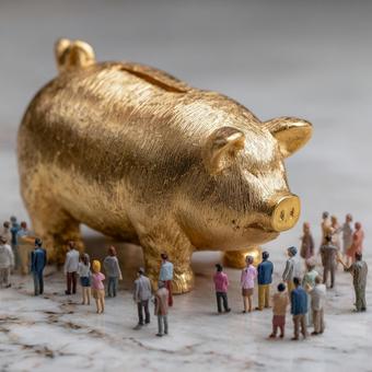 金の豚の貯金箱を見上げるミニチュアの人々の写真