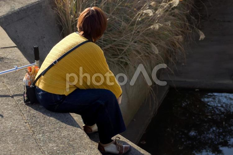 ※＜人物＞座り込み用水路を見詰める女性 女性,人物,風景の写真素材