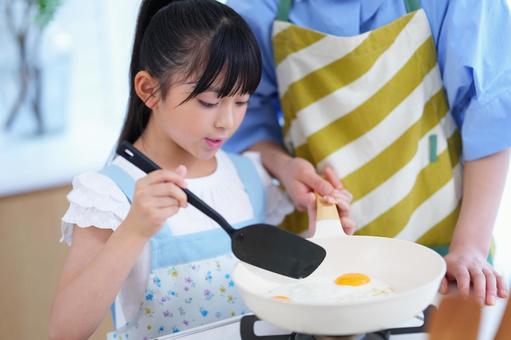 卵を割って朝食を作るエプロン姿の女の子 女の子,目玉焼き,焼くの写真素材