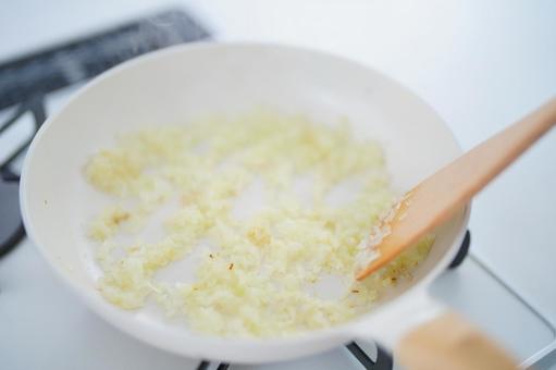 玉ネギを炒めるフライパンとターナーの写真