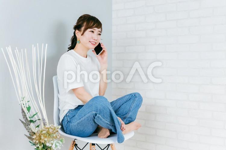 椅子に座りながらスマホを使うアジア人女性 スマホ,電話,通話の写真素材