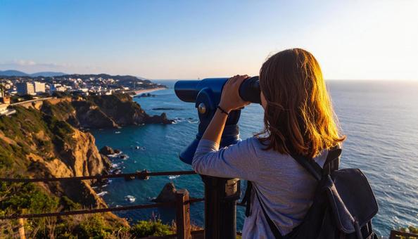 双眼鏡で海の先を見ている女性 双眼鏡で海の先を見ている女性の写真