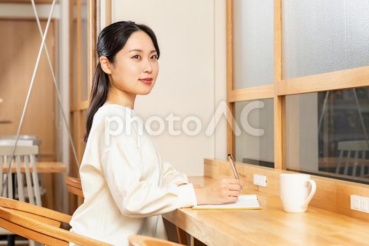 カフェでメモをするアジア人女性03 女性,メモ,考えるの写真素材