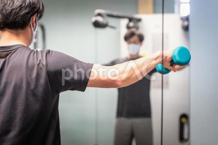 スポーツジムでダンベルを使う男性（マスク） ダンベル,負荷,筋トレの写真素材