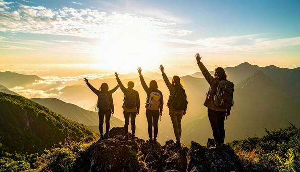 夏山で朝日に向かって手をあげる登山者の写真
