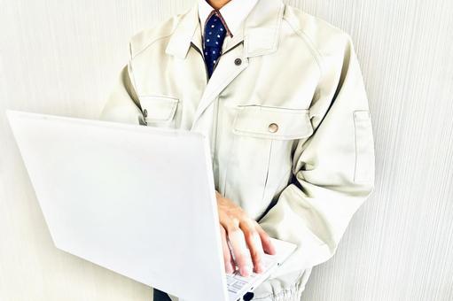 ノートパソコンを持つ作業着姿の男性 パソコン,作業員,男性の写真素材