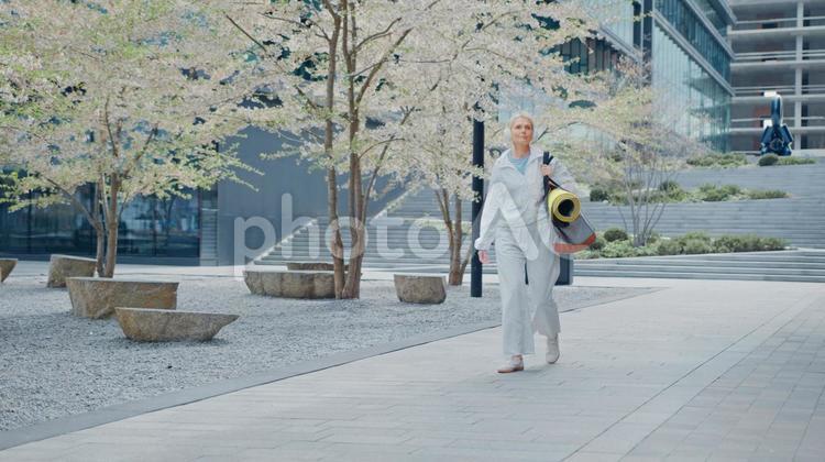ヘッドフォンをしてバッグを持って散歩する女性 女性,人物,元気の写真素材