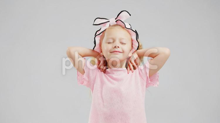 ピンクのヘアバンドをして目を瞑っている女の子 女の子,目を瞑る,ポーズの写真素材