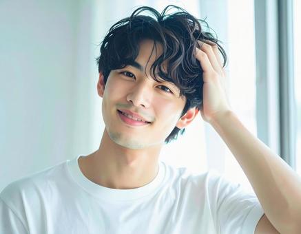 爽やかに髪を触る男性モデルの写真