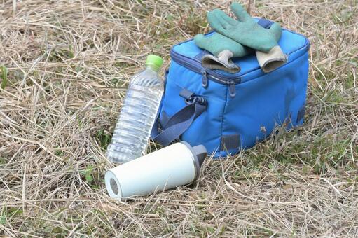 枯草の上に置かれた水分補給用のボトル クーラーバッグ,ペットボトル,雑草の写真素材