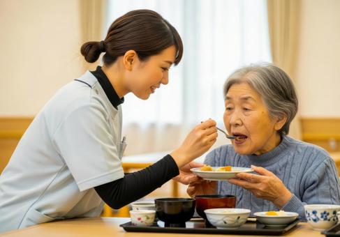女性介護士が高齢女性に食事介助する場面 女性介護士が高齢女性に食事介助する場面の写真