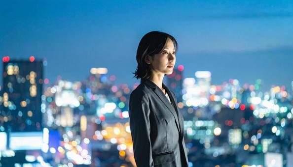 都市の夜景を背景に佇むビジネスマン 都市の夜景を背景に佇むビジネスマンの写真