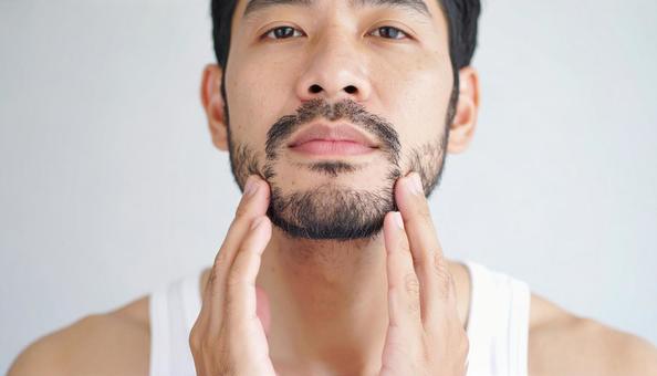 無精髭をさわる男性の手もと 無精髭をさわる男性の手もとの写真