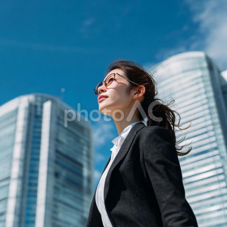 ビル街を颯爽と歩くビジネスウーマン 女性,ビジネスウーマン,青空の写真素材