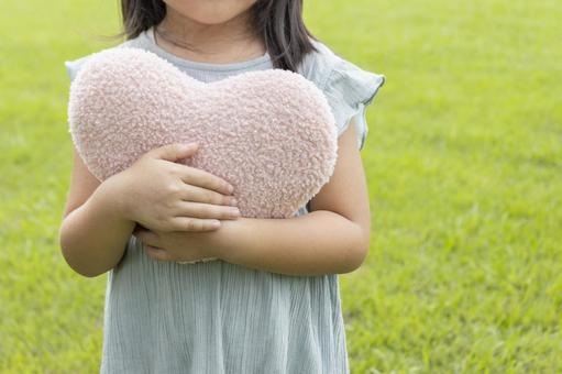 ハートのクッションを持って立つ女子（5歳 女の子,ハート,愛の写真素材