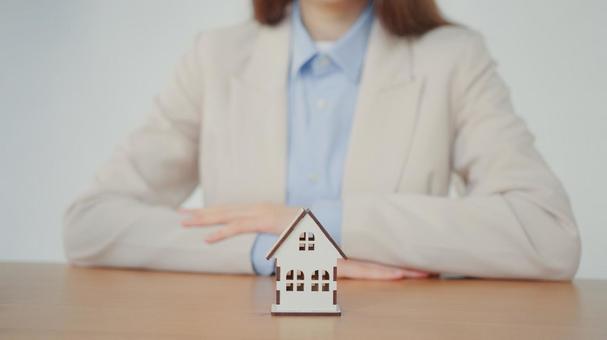 家の模型を前に腕組する女性 保険業,事務職,接客業の写真素材