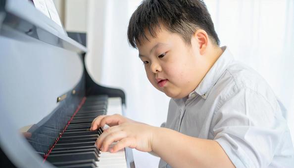 ピアノを弾くダウン症の少年 ピアノを弾くダウン症の少年の写真