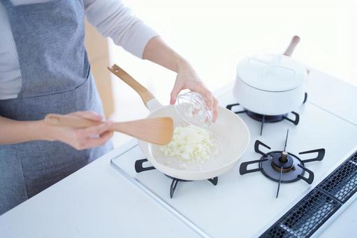 フライパンにみじん切りの玉ネギを入れる人の手 フライパンにみじん切りの玉ネギを入れる人の手の写真