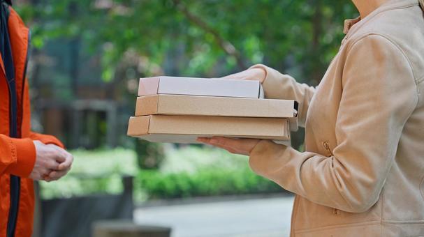 屋外でピザのデリバリーを受け取る女性 配達,フードデリバリー,デリバリーの写真素材